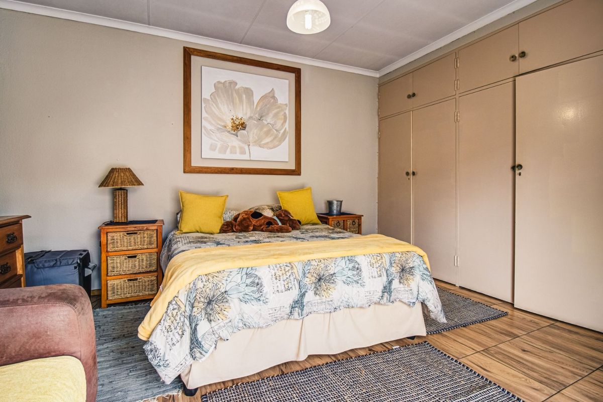 A well-maintained bedroom featuring built-in cupboards and durable laminate flooring, offering a functional and comfortable living space.