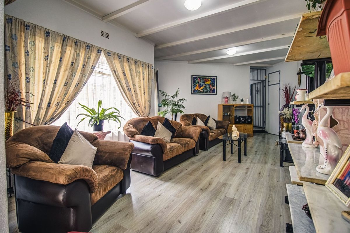 Spacious living room featuring light-toned laminate flooring and an exposed beam ceiling, offering a comfortable and functional layout.