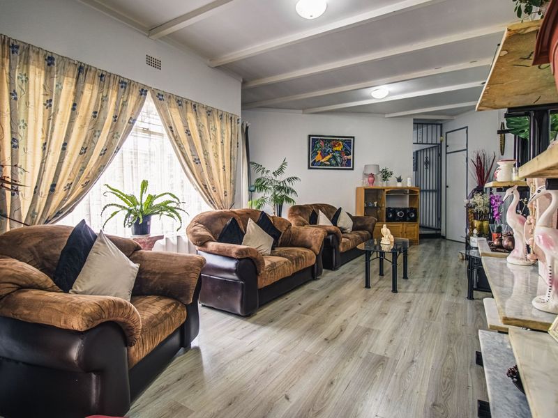 Spacious living room featuring light-toned laminate flooring and an exposed beam ceiling, offering a comfortable and functional layout.
