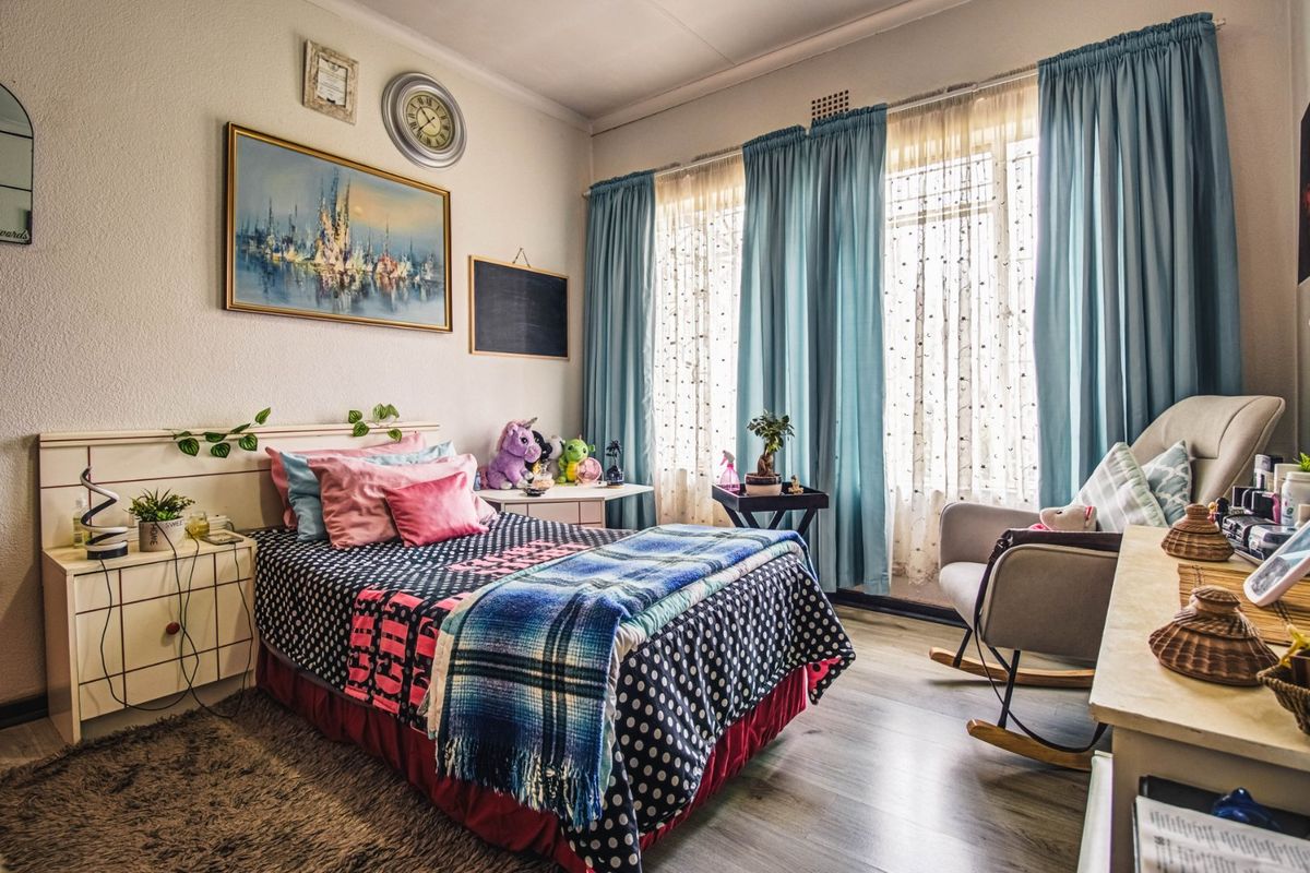 A well-lit bedroom featuring laminate flooring and a built-in headboard, offering a comfortable and functional living space.