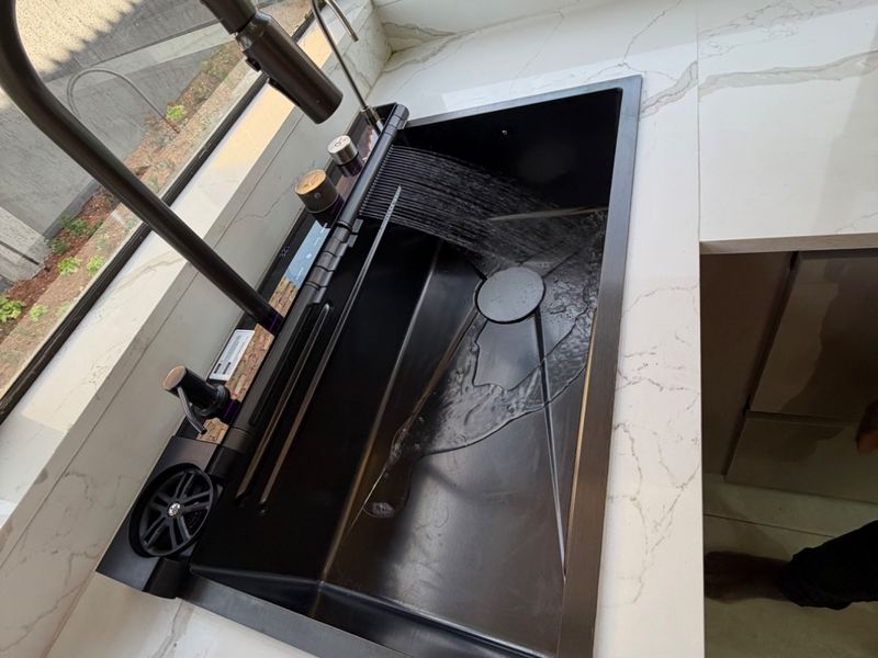 Modern kitchen featuring a sleek black integrated sink with a gooseneck faucet and premium marble-look quartz countertops.