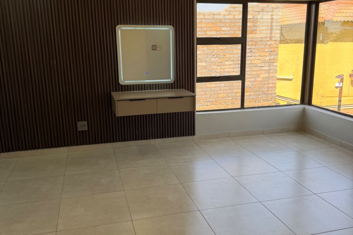 A bright, modern living area featuring large format floor tiles, a contemporary slatted wood feature wall, and a floating vanity with an integrated LED mirror.
