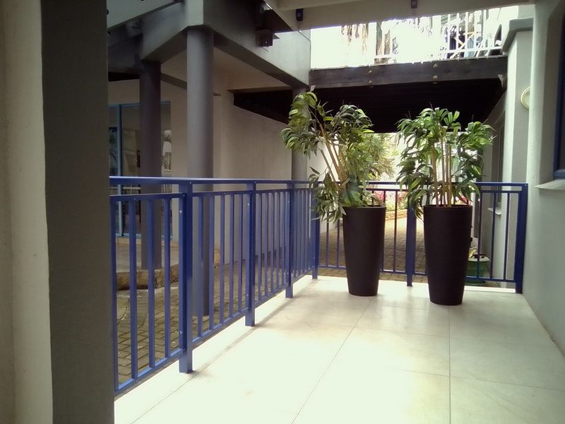 A covered balcony area featuring tiled flooring and a blue metal balustrade, providing a functional outdoor space.