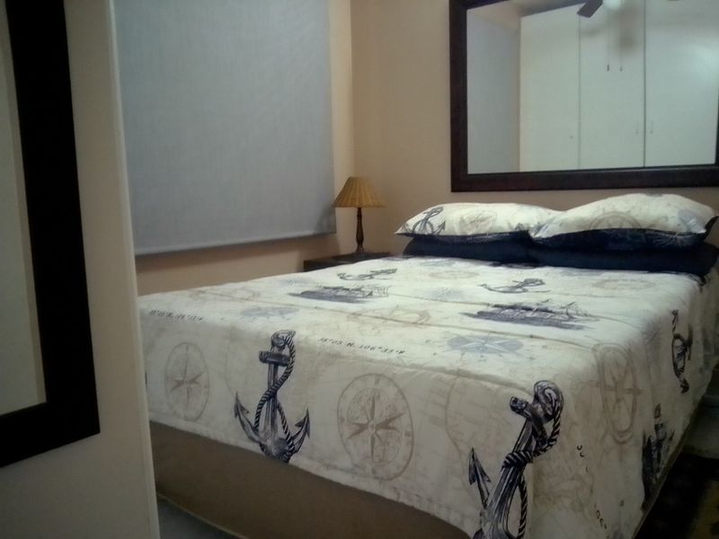 A bedroom featuring built-in cupboards, a ceiling fan, and a roller blind, providing a functional sleeping space.