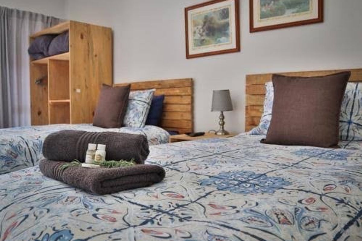 A cozy bedroom featuring twin beds with patterned bedding and integrated wooden shelving units.