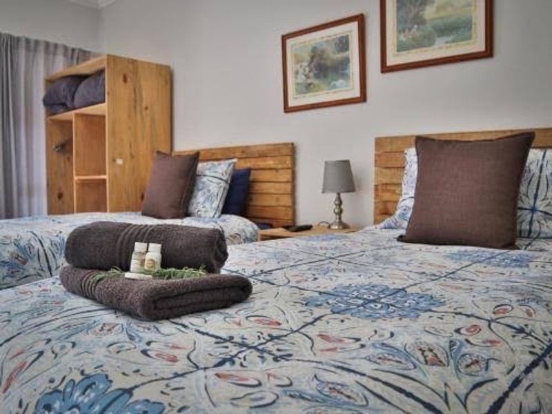 A cozy bedroom featuring twin beds with patterned bedding and integrated wooden shelving units.