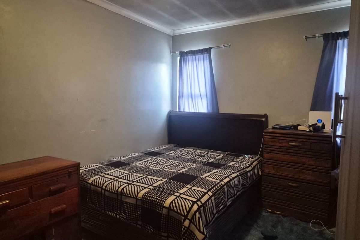 A standard bedroom featuring neutral wall paint, coving, and dual window treatments. The space requires cosmetic updates to improve its overall condition.