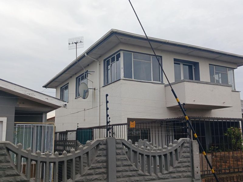 Front exterior view of a two-story house featuring a balcony, electric fencing, and precast concrete boundary walling.