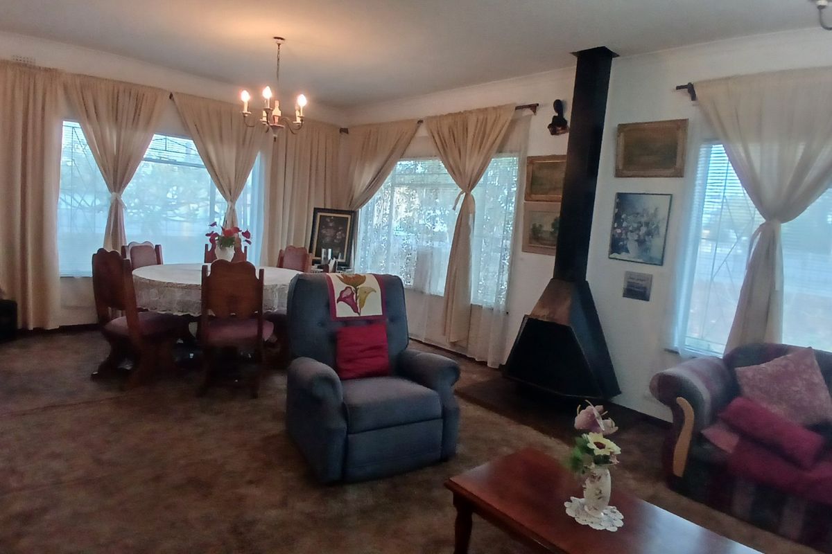 Spacious living room featuring a prominent black freestanding fireplace, large windows with natural light, and traditional ceiling lighting.