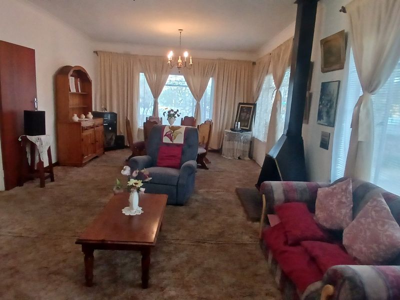 Spacious open-plan living and dining area featuring a central fireplace, carpeted flooring, and large windows with natural light.
