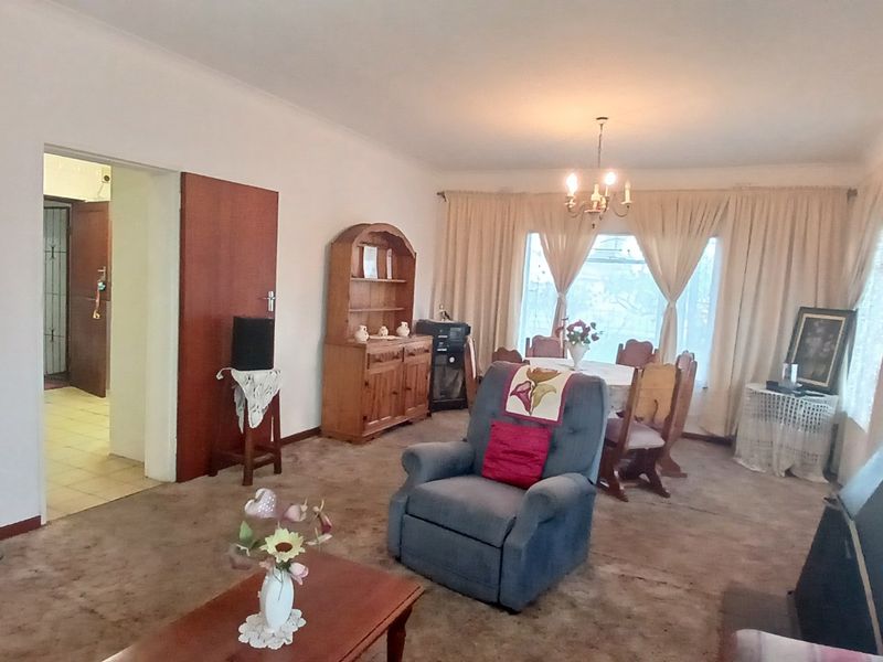 Open plan living and dining area featuring a fireplace, coving, and a chandelier, offering a spacious layout with potential for modernization.