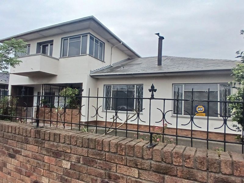 Front elevation of a two-story house featuring a brick boundary wall, wrought iron fencing, a tiled roof, and a balcony.