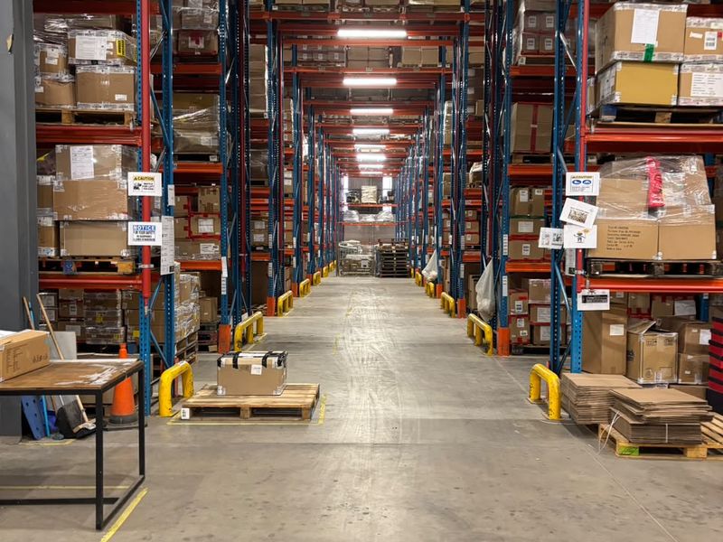 Industrial warehouse interior featuring high-density pallet racking systems, concrete flooring, and overhead fluorescent lighting for efficient storage and logistics operations.