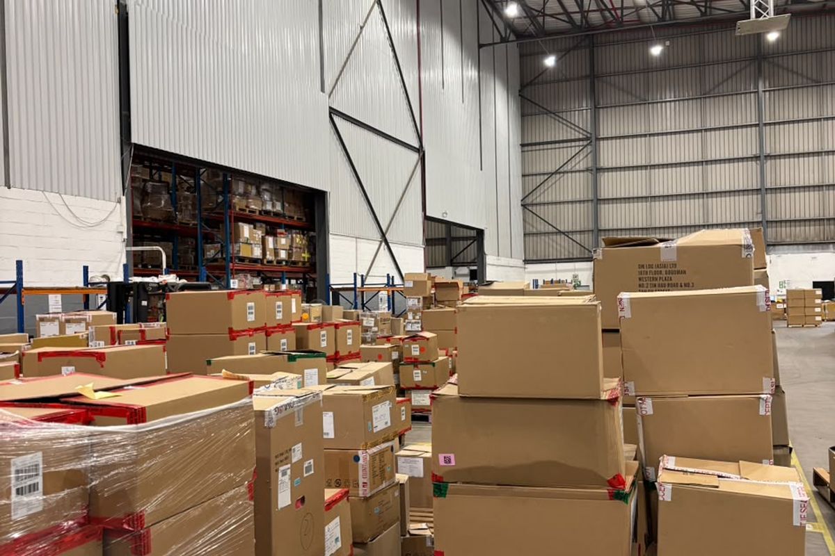 Spacious industrial warehouse featuring high ceilings with exposed steel trusses, high-bay lighting, and durable concrete flooring, currently utilized for storage.