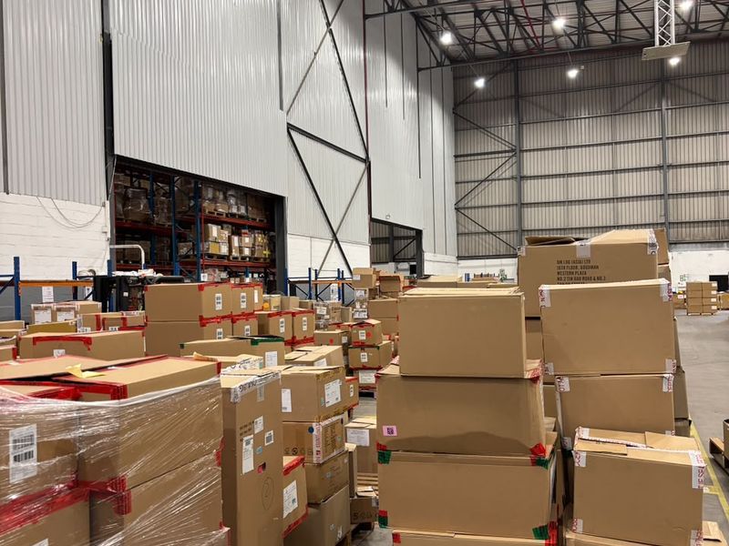 Spacious industrial warehouse featuring high ceilings with exposed steel trusses, high-bay lighting, and durable concrete flooring, currently utilized for storage.