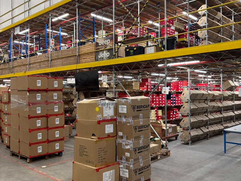 Spacious industrial warehouse featuring high-level steel racking, mezzanine storage, durable concrete flooring, and efficient overhead fluorescent lighting.