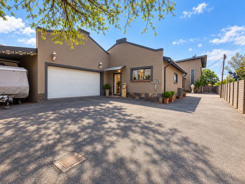 Front elevation of the property featuring a paved driveway, integrated garage, and stone-accented exterior walls.
