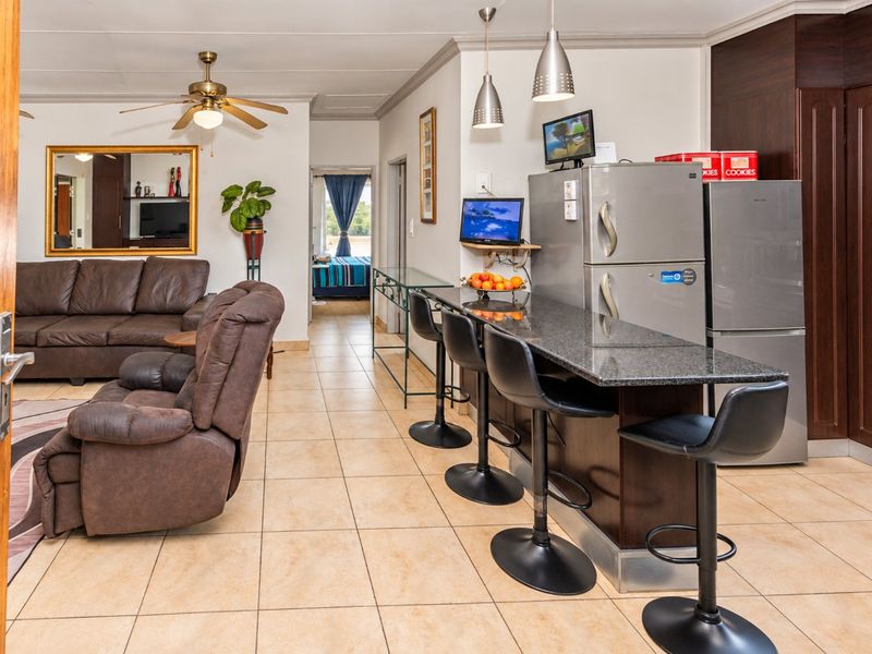 Open-plan living area featuring tiled flooring, a granite breakfast bar, and built-in cabinetry, creating a functional and connected space.
