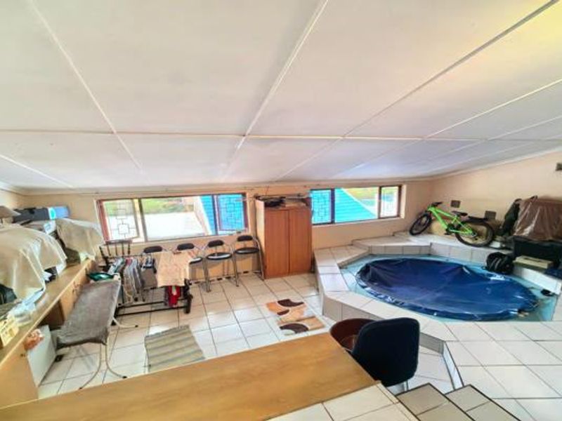 Indoor pool area featuring tiled flooring, large windows, and built-in cabinetry, offering a versatile space for recreation and leisure.
