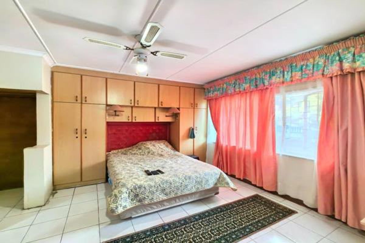 A bedroom featuring extensive built-in cabinetry, tiled flooring, and a ceiling fan, offering a functional layout with potential for modern updates.