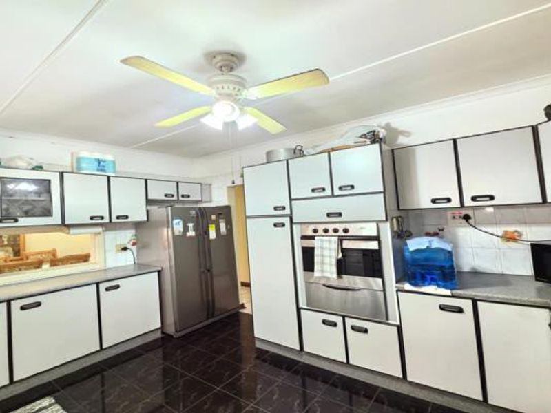 A functional kitchen featuring white built-in cabinetry, a built-in oven, dark tiled flooring, and a convenient pass-through window to the adjacent living area.
