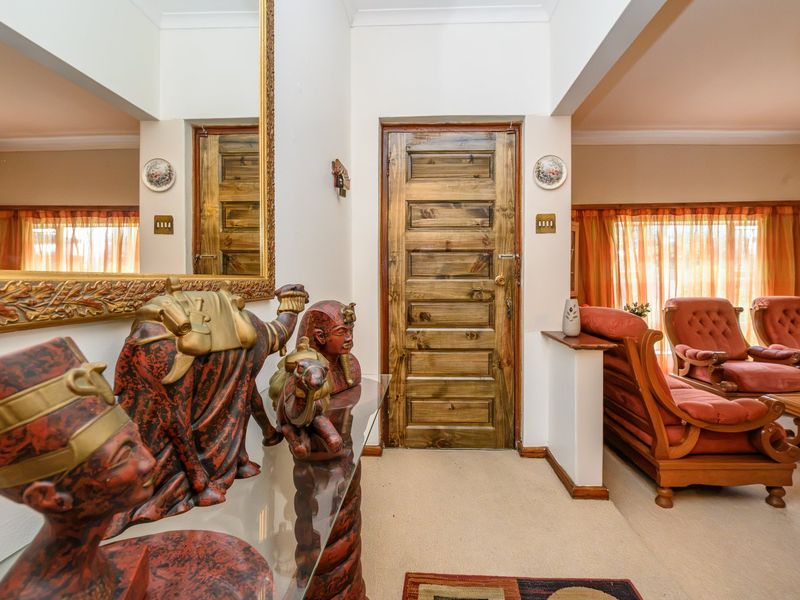 A welcoming entrance hall featuring a solid timber door, coved cornicing, and neutral carpeting, providing a clear transition into the main living area.