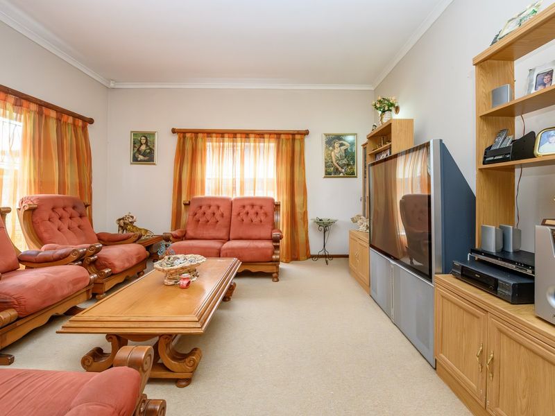 A living room featuring neutral wall tones, carpeted flooring, and a built-in wooden shelving unit.