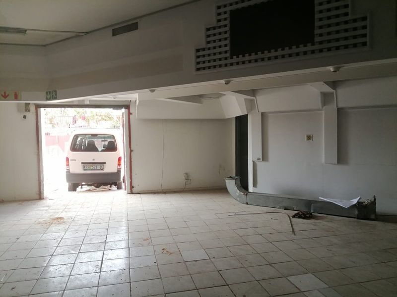 An empty commercial utility space featuring ceramic tiled flooring, recessed lighting, and exposed air conditioning ducting, suitable for various business or storage applications.
