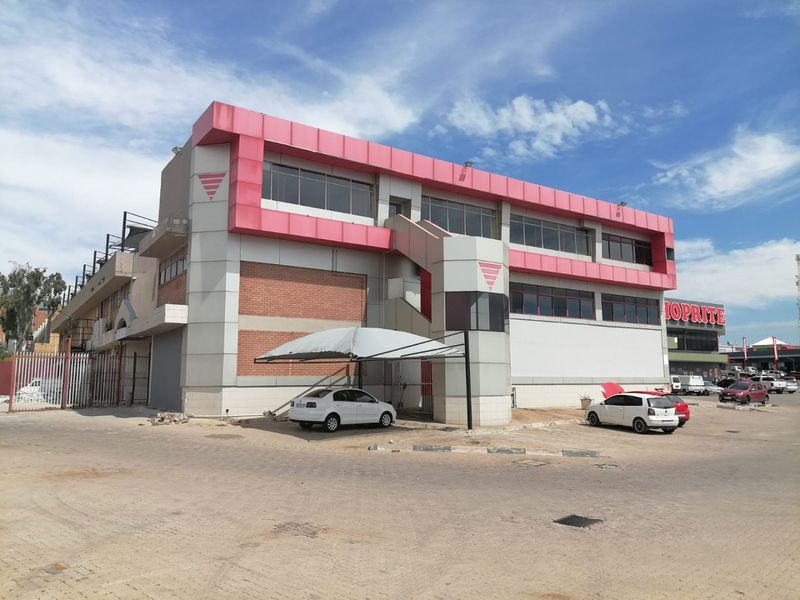 Commercial building exterior featuring metal cladding, brick accents, an external staircase, and a paved parking area with a shade port.