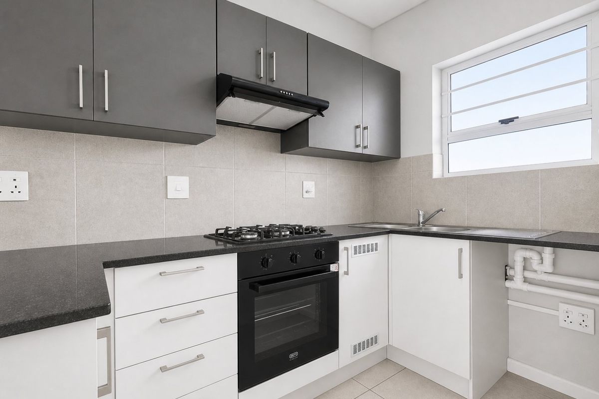Modern kitchen featuring sleek grey and white cabinetry, granite countertops, a gas hob, built-in oven, and a tiled backsplash.