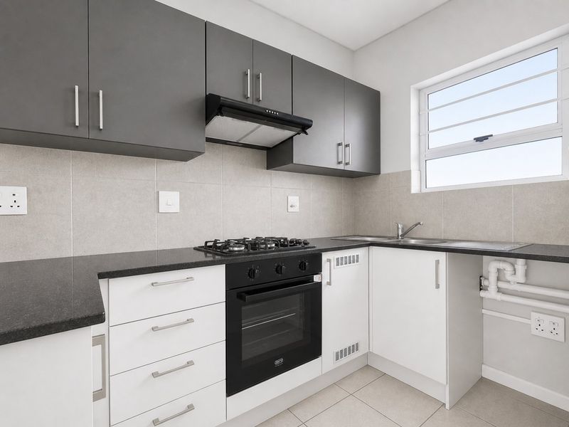 Modern kitchen featuring sleek grey and white cabinetry, granite countertops, a gas hob, built-in oven, and a tiled backsplash.