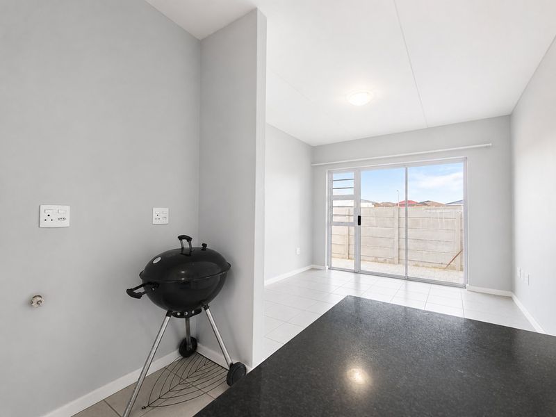 An open-plan living area featuring tiled flooring, a granite countertop, and a sliding glass door leading to an outdoor space.