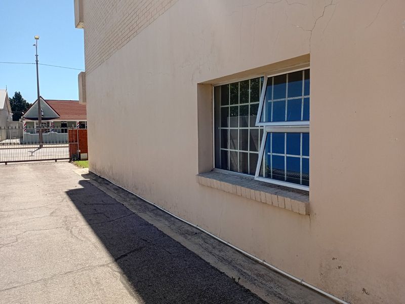Exterior view of the apartment building showing a side facade with security-barred windows and visible plaster cracking.