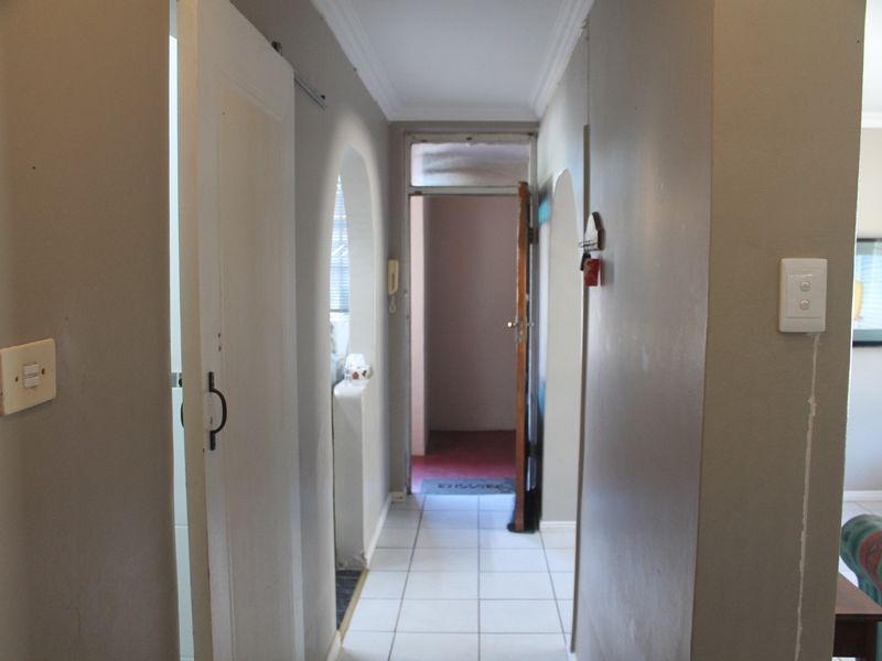 A functional hallway featuring ceramic floor tiles, arched transitions, and built-in intercom system, connecting various areas of the apartment.