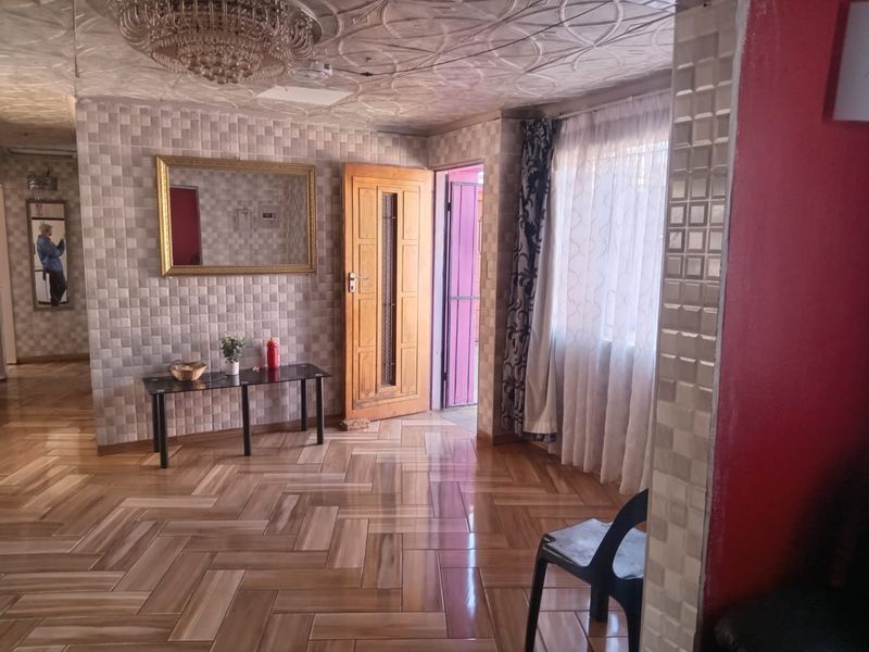 Living area featuring patterned tiled flooring, a decorative textured ceiling with a crystal chandelier, and tiled wall accents.
