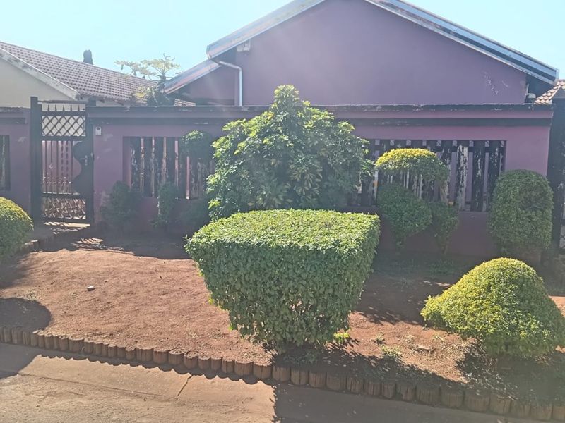 Front view of the property featuring a perimeter wall, metal gate, and a landscaped garden area with timber edging.