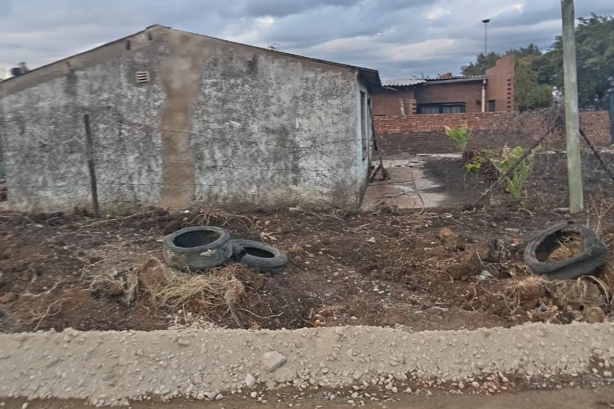 View of the property exterior from an unpaved road, showing the building facade and surrounding grounds.