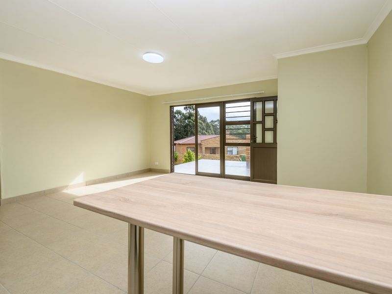 A bright, empty living room featuring neutral tiled flooring, coved ceilings, and a sliding glass door providing access to the outdoor area.