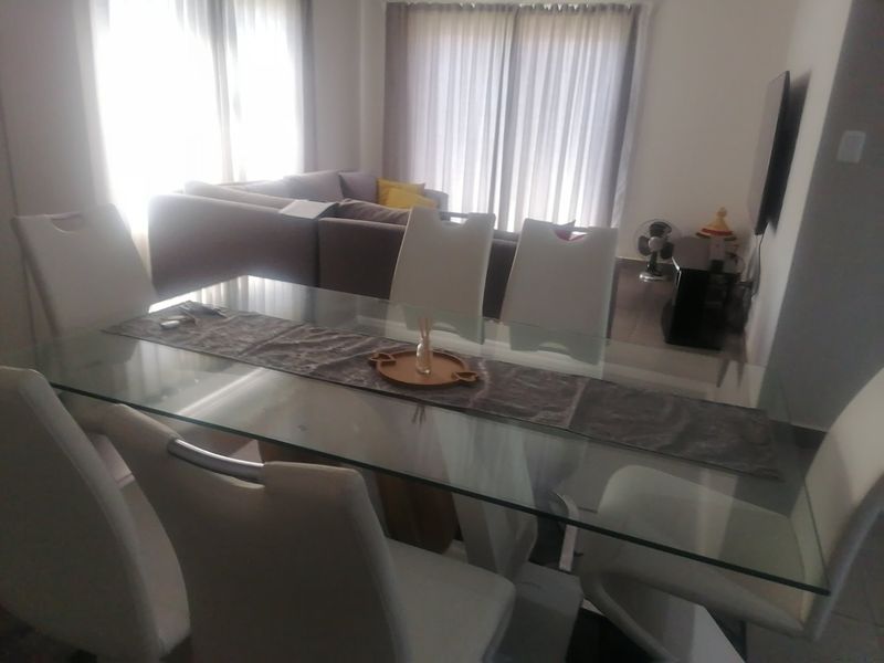 An open-plan living and dining area featuring tiled flooring and large sliding glass doors that provide natural light.