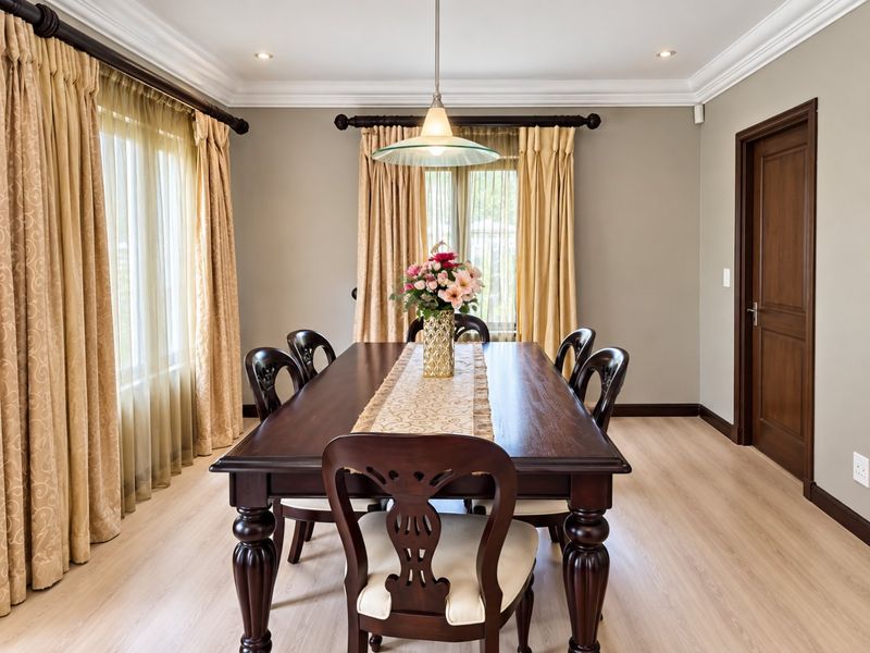 A well-maintained dining room featuring laminate flooring, crown molding, recessed lighting, and a central pendant light fixture.