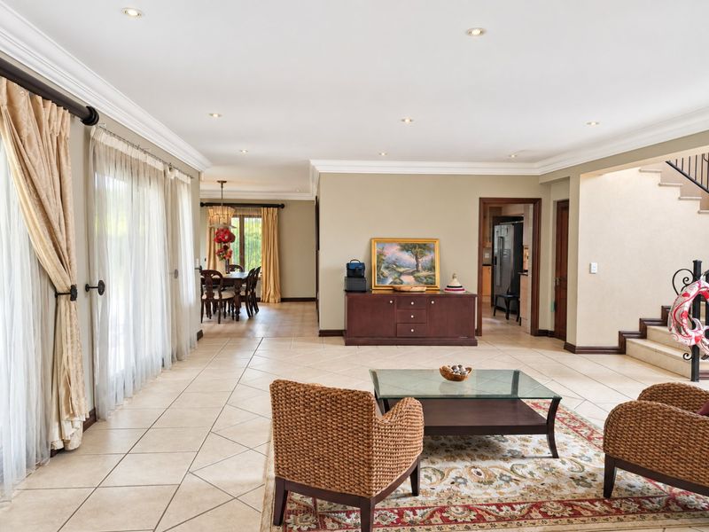 Spacious open-plan living and dining area featuring tiled floors, recessed lighting, crown molding, and direct access to the outdoor area via sliding glass doors.
