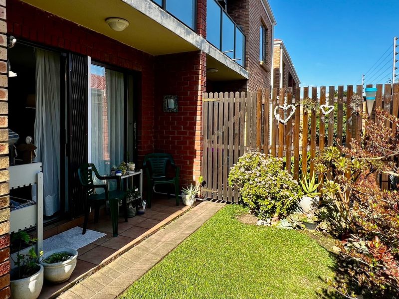 A ground-floor patio area featuring tiled flooring, direct access via sliding glass doors, and a private fenced garden space.