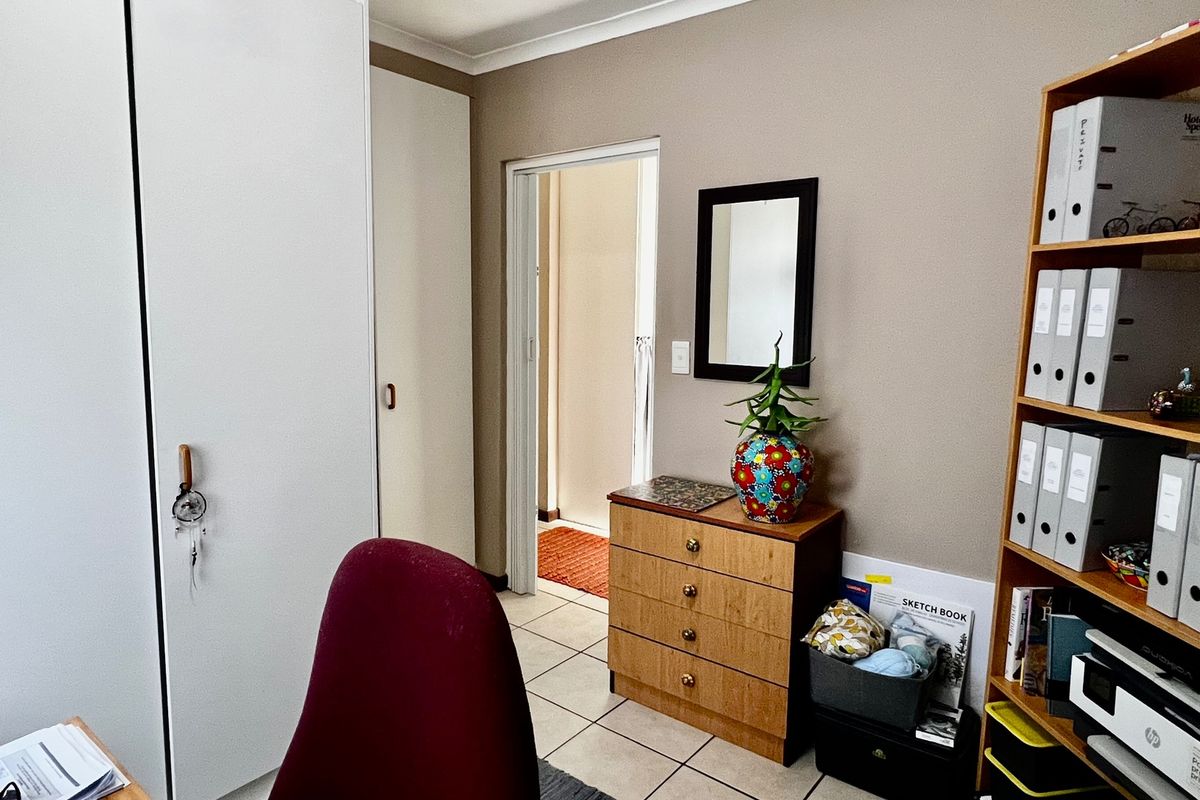 A bedroom featuring built-in cupboards, tiled flooring, and coved ceiling details, providing a functional space with neutral wall tones.
