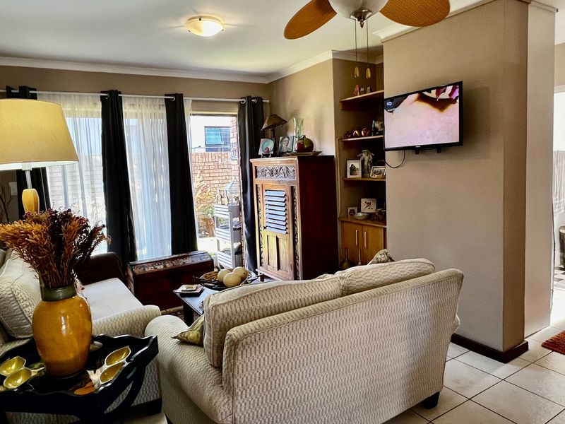 A comfortable living room featuring tiled flooring, a ceiling fan, and built-in shelving, with direct access to an outdoor patio area.