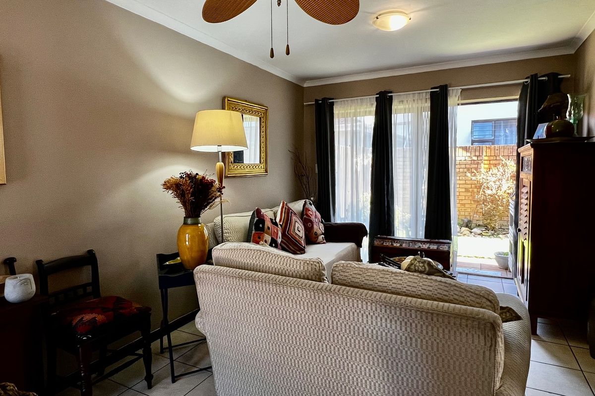 A comfortable living room featuring tiled flooring, a ceiling fan, and a sliding glass door providing access to an outdoor patio area.
