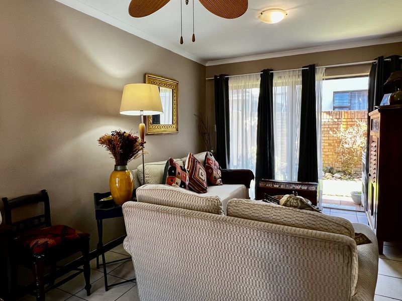 A comfortable living room featuring tiled flooring, a ceiling fan, and a sliding glass door providing access to an outdoor patio area.