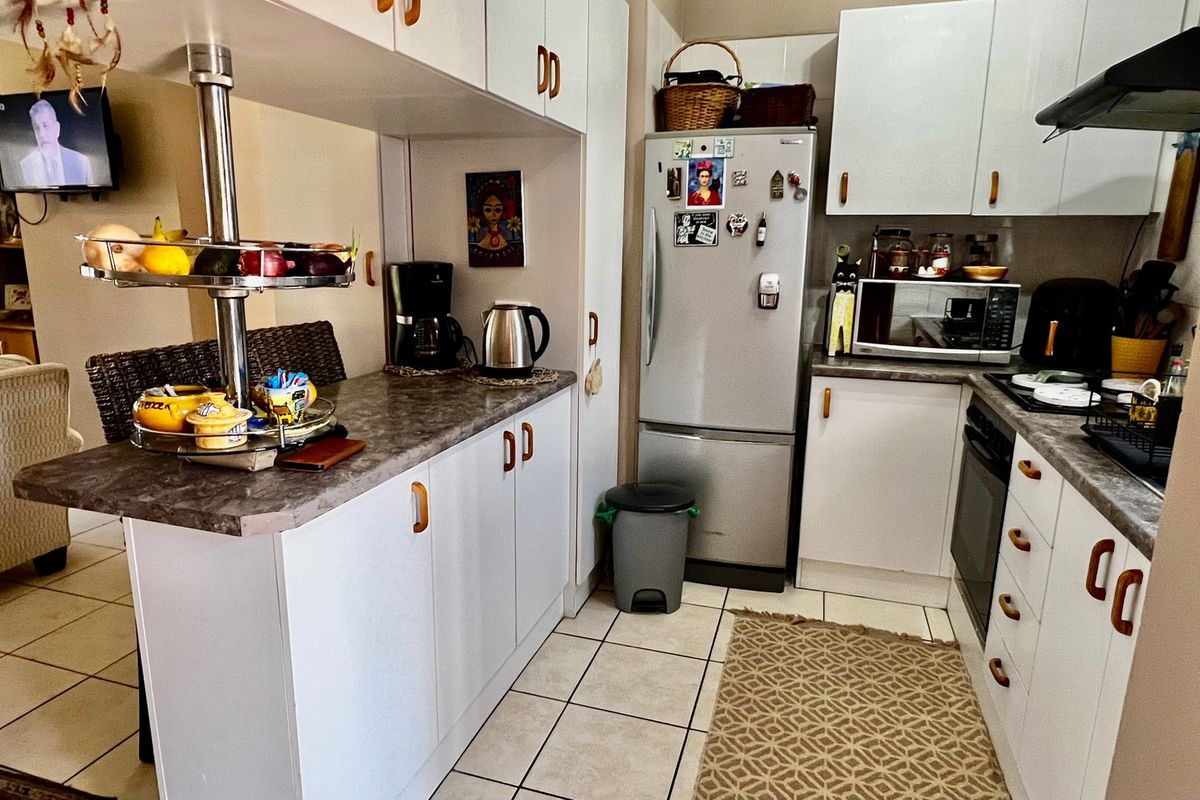 A functional kitchen featuring white cabinetry, laminate countertops, a breakfast bar, and ceramic floor tiles, providing a practical layout for daily use.