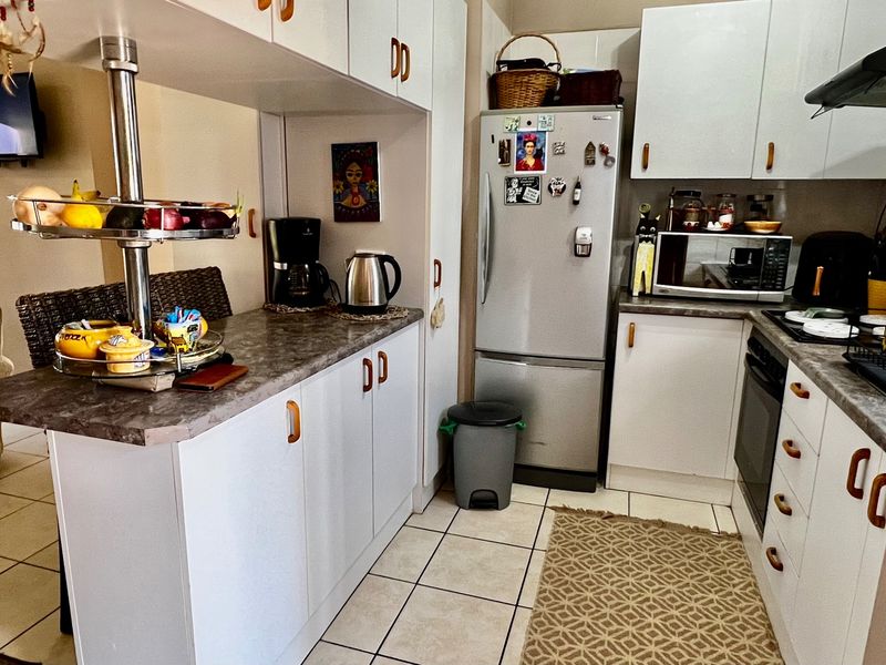 A functional kitchen featuring white cabinetry, laminate countertops, a breakfast bar, and ceramic floor tiles, providing a practical layout for daily use.