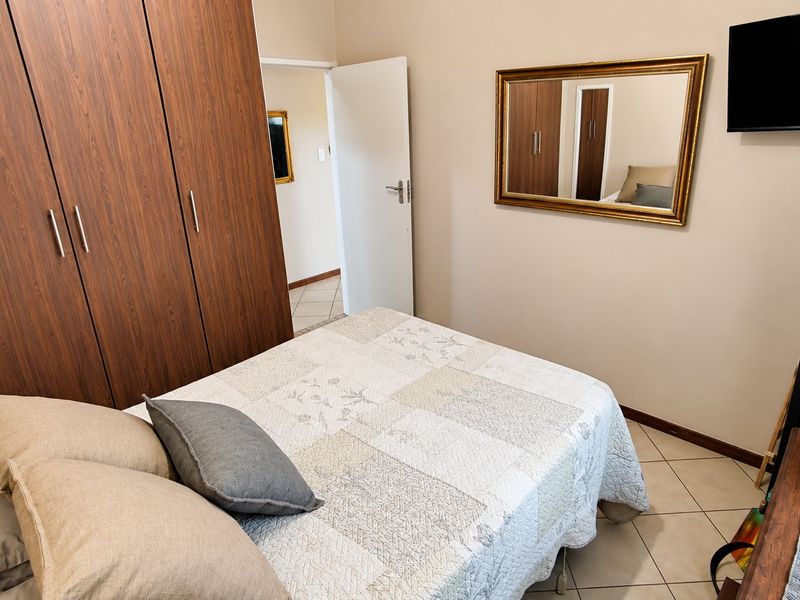 A functional bedroom featuring built-in wooden cupboards and tiled flooring, providing a practical and well-maintained living space.