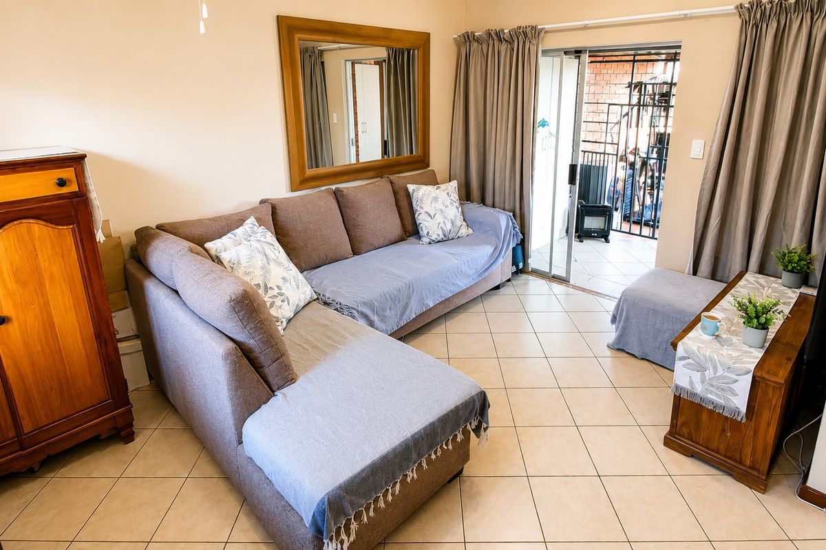 A living room featuring ceramic floor tiles and a sliding glass door providing access to an outdoor patio area.